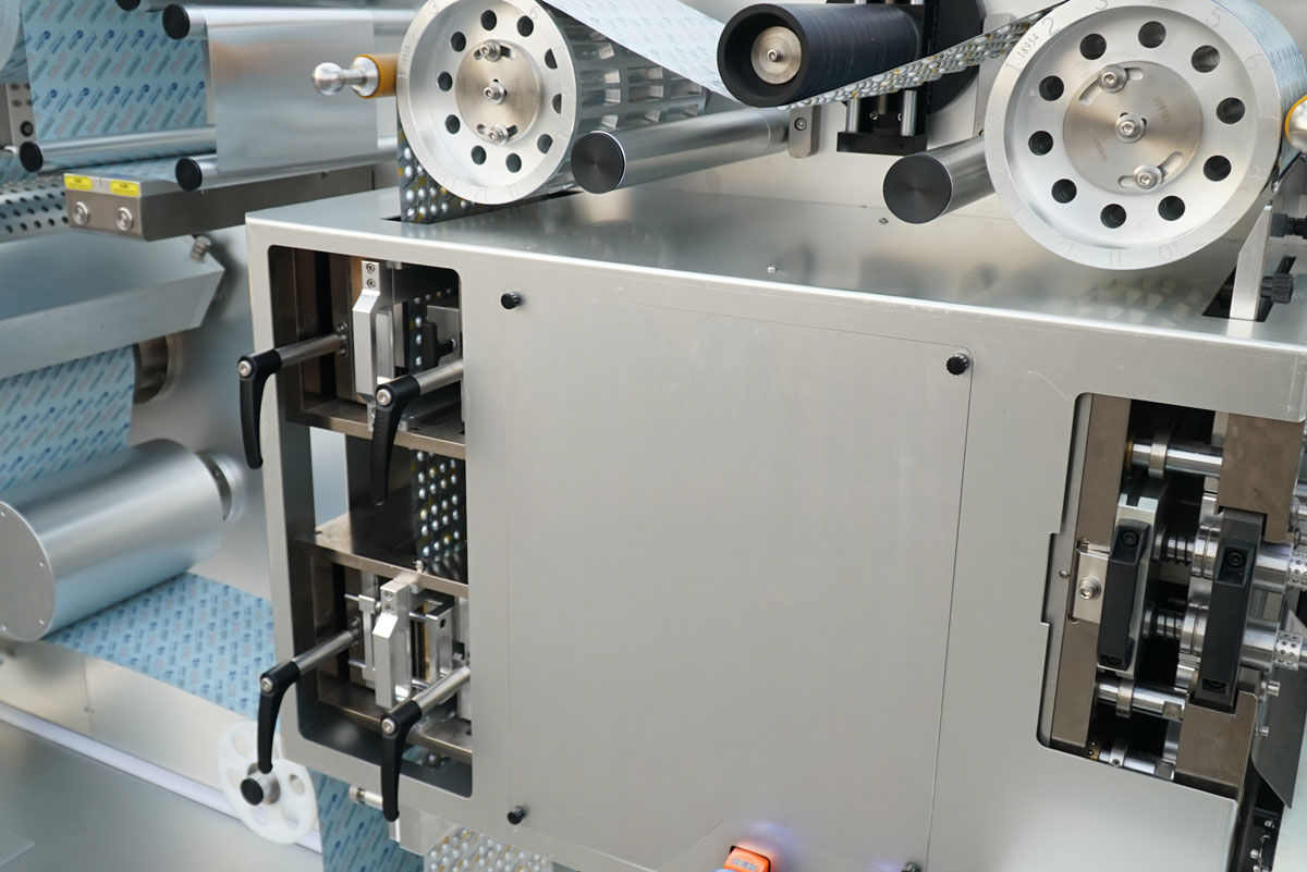 BMR270 Blister Machine - Perforation and Embossing Station Close-up of the integrated perforation and embossing station on the BMR270 blister packaging machine, applying precision tear-notches and permanent alphanumeric coding for strict pharmaceutical traceability.