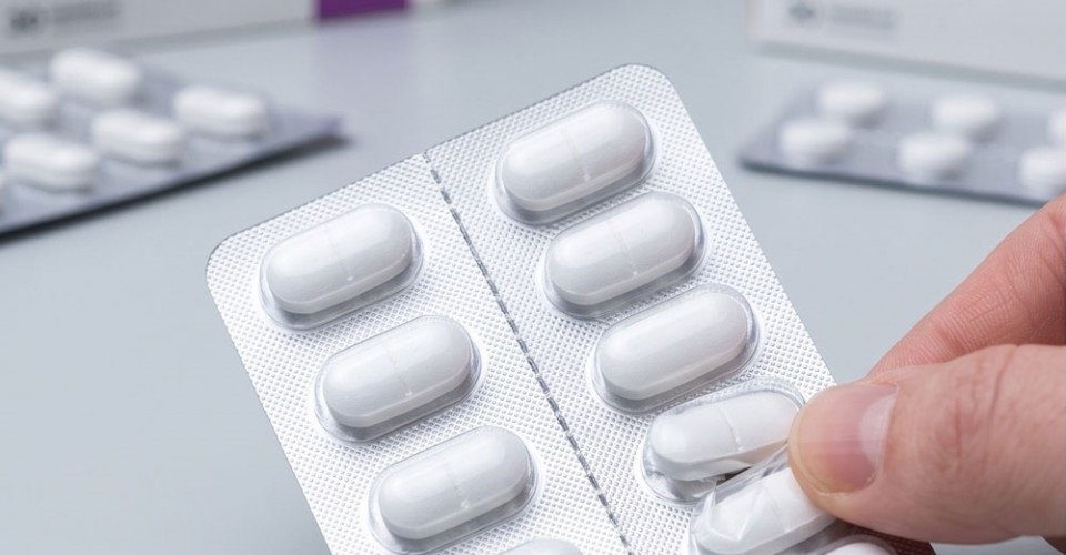 Hand separating a pharmaceutical blister pack along the perforated line for unit-dose dispensing